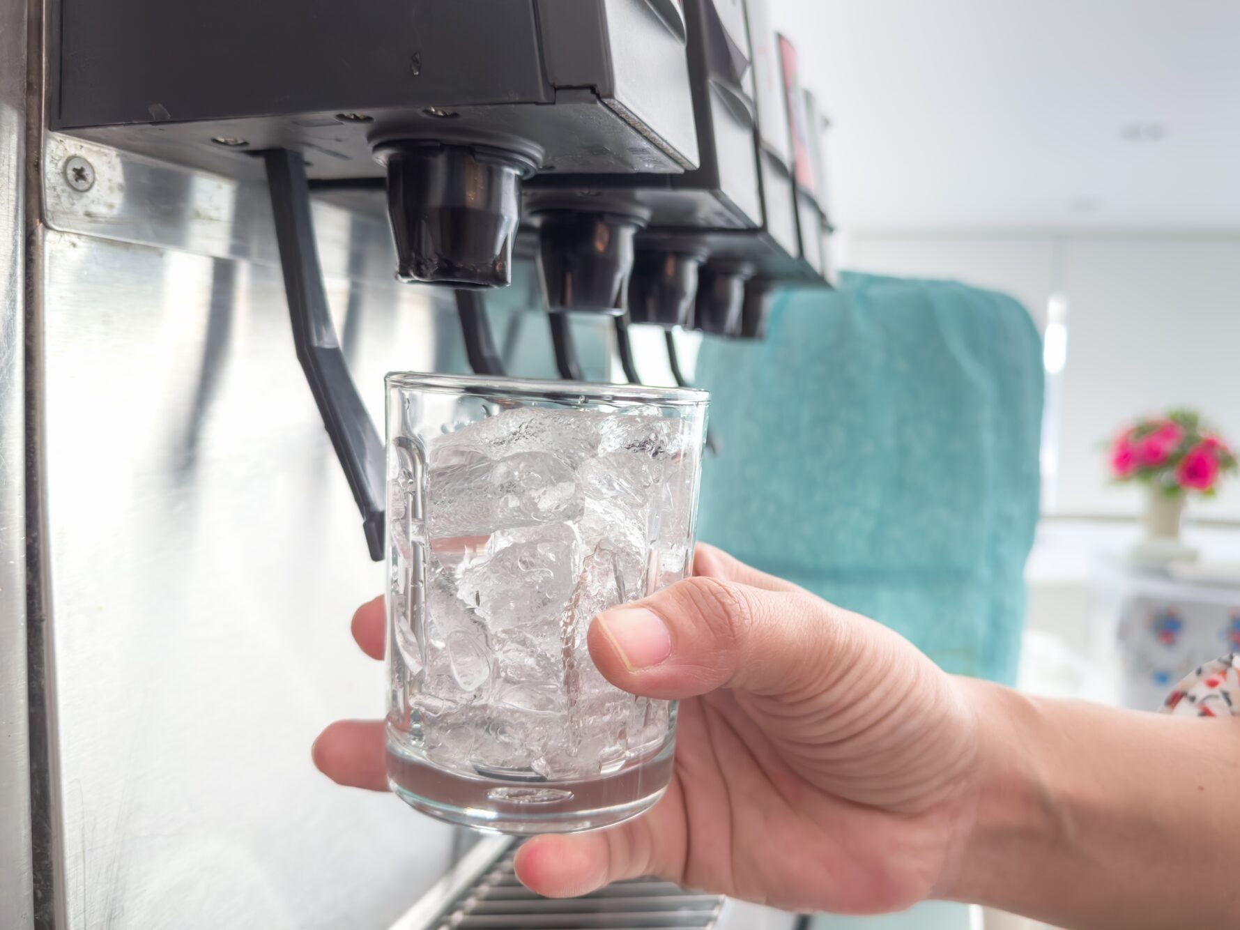 glass with ice is raised toward soda fountain to be filled with a beverage