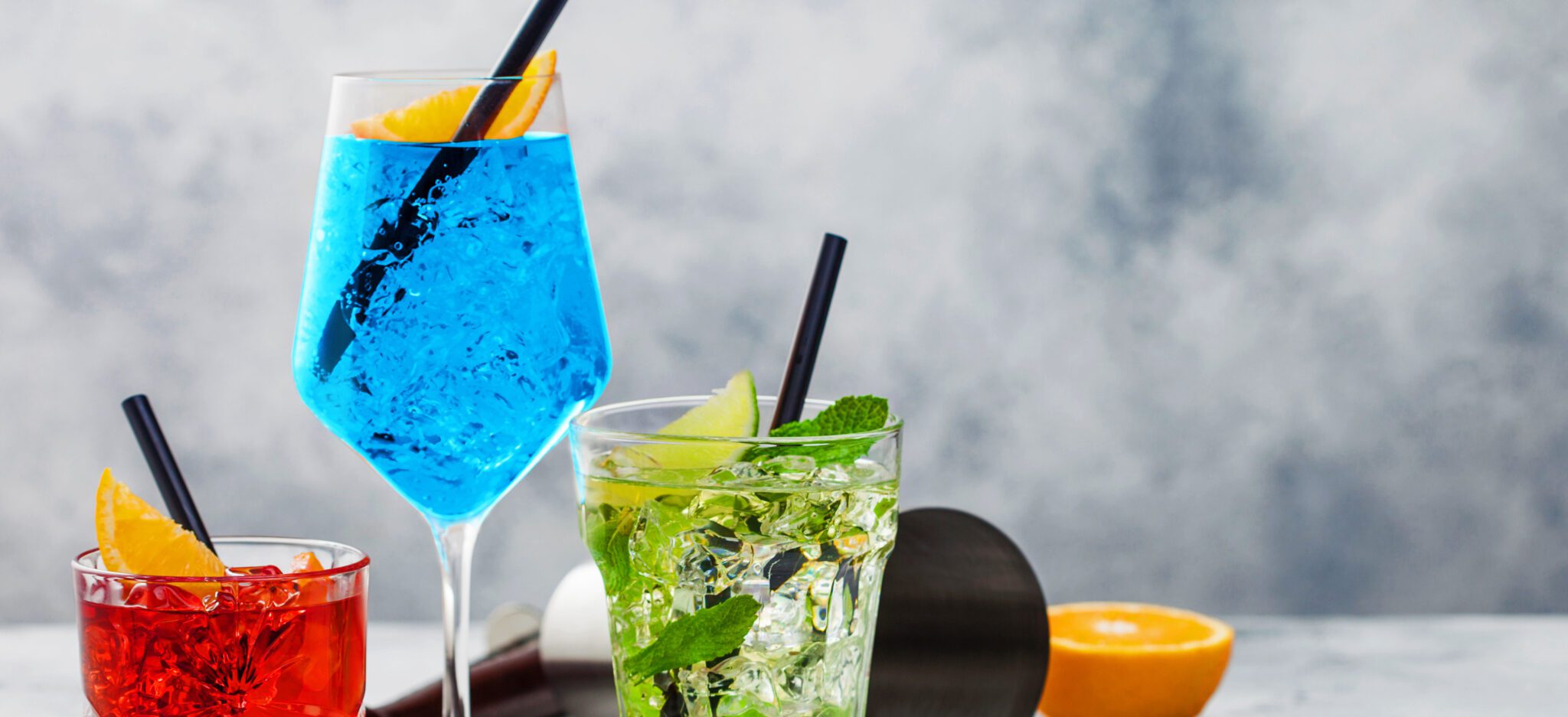 red, blue, and green cocktails in glasses with ice